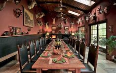 a long wooden table with place settings and deer heads hanging from the ceiling above it