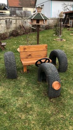 a wooden bench made out of old tires in the grass next to a pile of junk