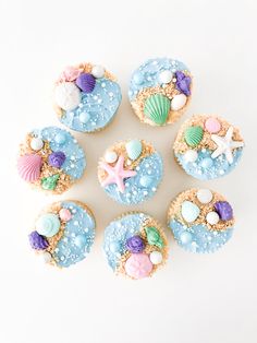 there are six cupcakes decorated with seashells and starfish on them