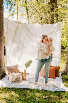 a woman holding a baby in her arms while standing next to a white tarp