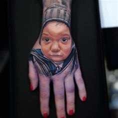 a woman's hand with a tattoo on it that has a portrait of a child