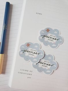 a notebook with some stickers on it next to a pen