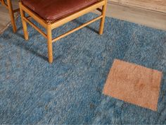 a brown chair sitting on top of a blue rug