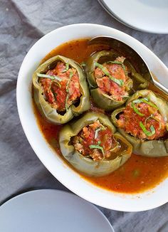 a white bowl filled with stuffed peppers covered in sauce