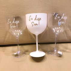 three wine glasses with writing on them sitting next to each other in front of a wall