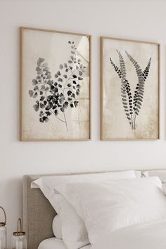 two paintings on the wall above a bed in a room with white sheets and pillows