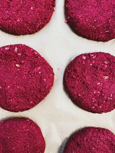 six red cookies sitting on top of a baking pan covered in pink powdered sugar