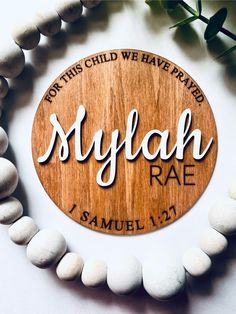 a wooden sign with the name of a child is displayed on a beaded bracelet