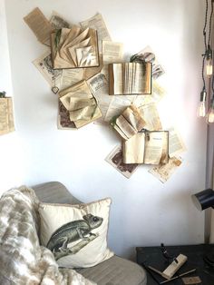 an old book is hanging on the wall next to a chair with pillows and a lamp