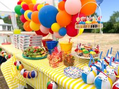 a table topped with lots of balloons next to a yellow and white striped table cloth