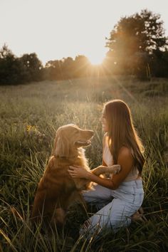 a woman is sitting in the grass with her golden retriever, who is looking into the distance