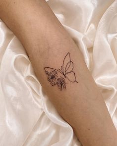 a woman's arm with a butterfly and flowers tattoo on the left side of her leg