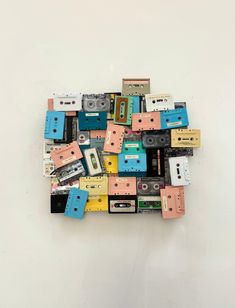 a pile of cassettes sitting on top of each other in front of a white wall