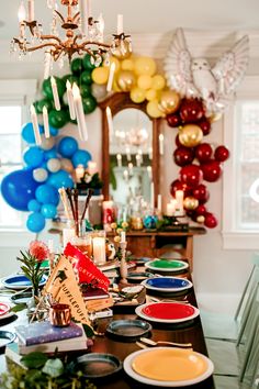 a dining room table with plates, candles and balloons on the wall in the background