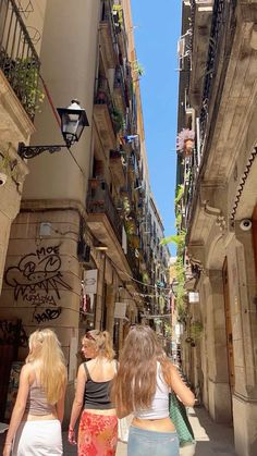 three women walking down an alley way with buildings in the background