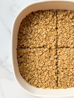 baked oatmeal squares in a white dish on a marble counter top, ready to be eaten