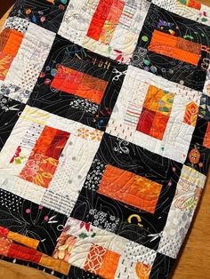 an orange and black quilt on a wooden table