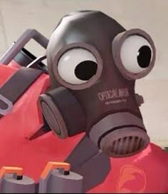 a gas mask sitting on top of a red suitcase with eyes wide open and one eye partially closed