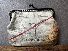 a map purse sitting on top of a wooden table in front of a gray wall