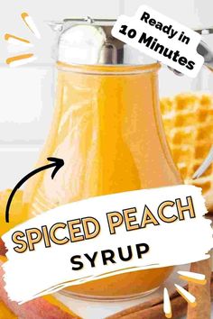 a bottle of spiced peach syrup next to some waffles and cinnamon sticks