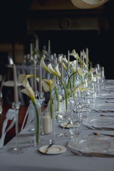 a long table is set with wine glasses and flowers in vases on the tables