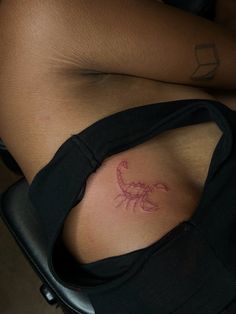 a woman's stomach with a scorpion tattoo on her left side ribcage