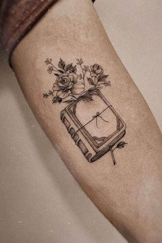 a tattoo on the leg of a woman with flowers and an old tv in it