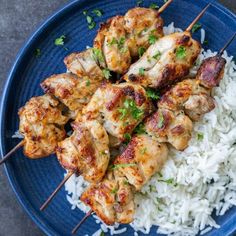 chicken skewers and rice on a blue plate