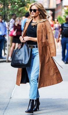 a woman walking down the street carrying a black bag