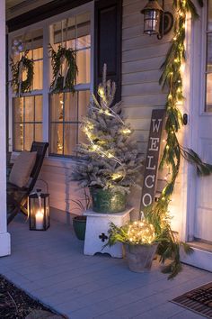 a porch decorated for christmas with lights and greenery