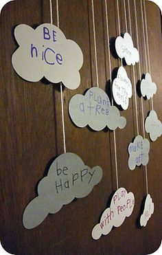 some paper clouds hanging from strings with writing on them