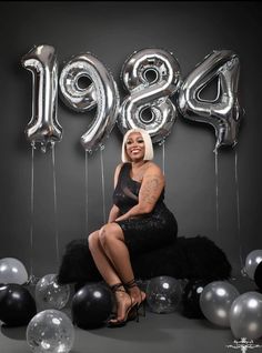 a woman sitting in front of balloons with the number 949 written on it,