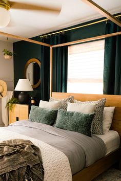 a bed with green and white pillows in a bedroom next to a lamp on a dresser