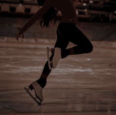 a woman skating on an ice rink in the dark with her arms out and legs spread wide