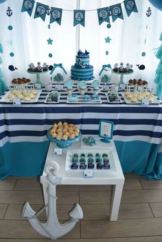 a table topped with blue and white desserts next to a window covered in curtains