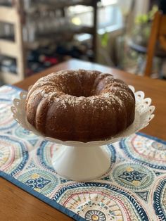 a bundt cake sitting on top of a white pedestal next to a blue and white place mat