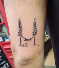 a man's arm with trees and a hammock tattoo on it