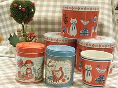 several tins are stacked on top of each other in front of a checkered tablecloth