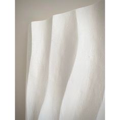 a white curtain hanging on the side of a wall in front of a light colored wall