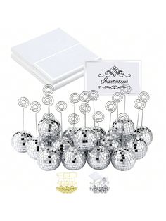 a bunch of silver disco balls sitting on top of a table next to a card