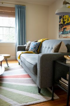 a living room filled with furniture and a rug on top of a hard wood floor