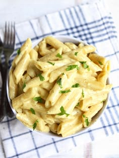 a white bowl filled with macaroni and cheese on top of a checkered table cloth