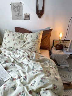 an unmade bed in a white room with books on the floor and pictures hanging above it