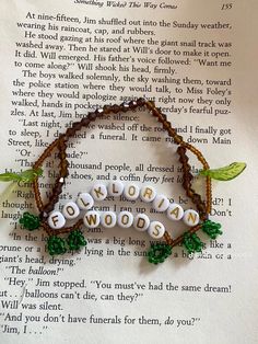 a beaded bracelet with words written in white and green beads on top of an open book