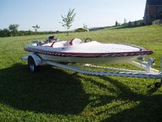 a white and red boat parked in the grass