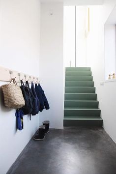 there is a set of stairs leading up to the second floor with coats hanging on hooks