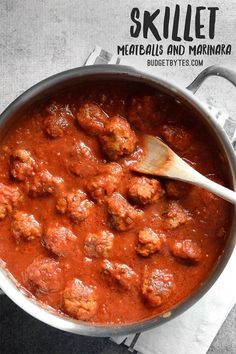 a skillet filled with meatballs and marinara on top of a white napkin