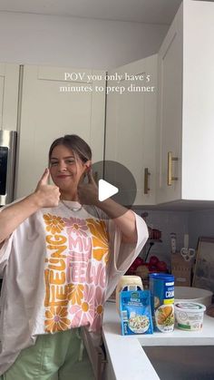 a woman standing in a kitchen giving the thumbs up