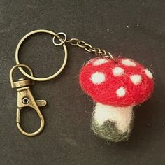 a red and white mushroom keychain sitting on top of a black table next to a pair of scissors