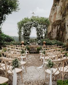 an outdoor ceremony setup with wooden chairs and greenery